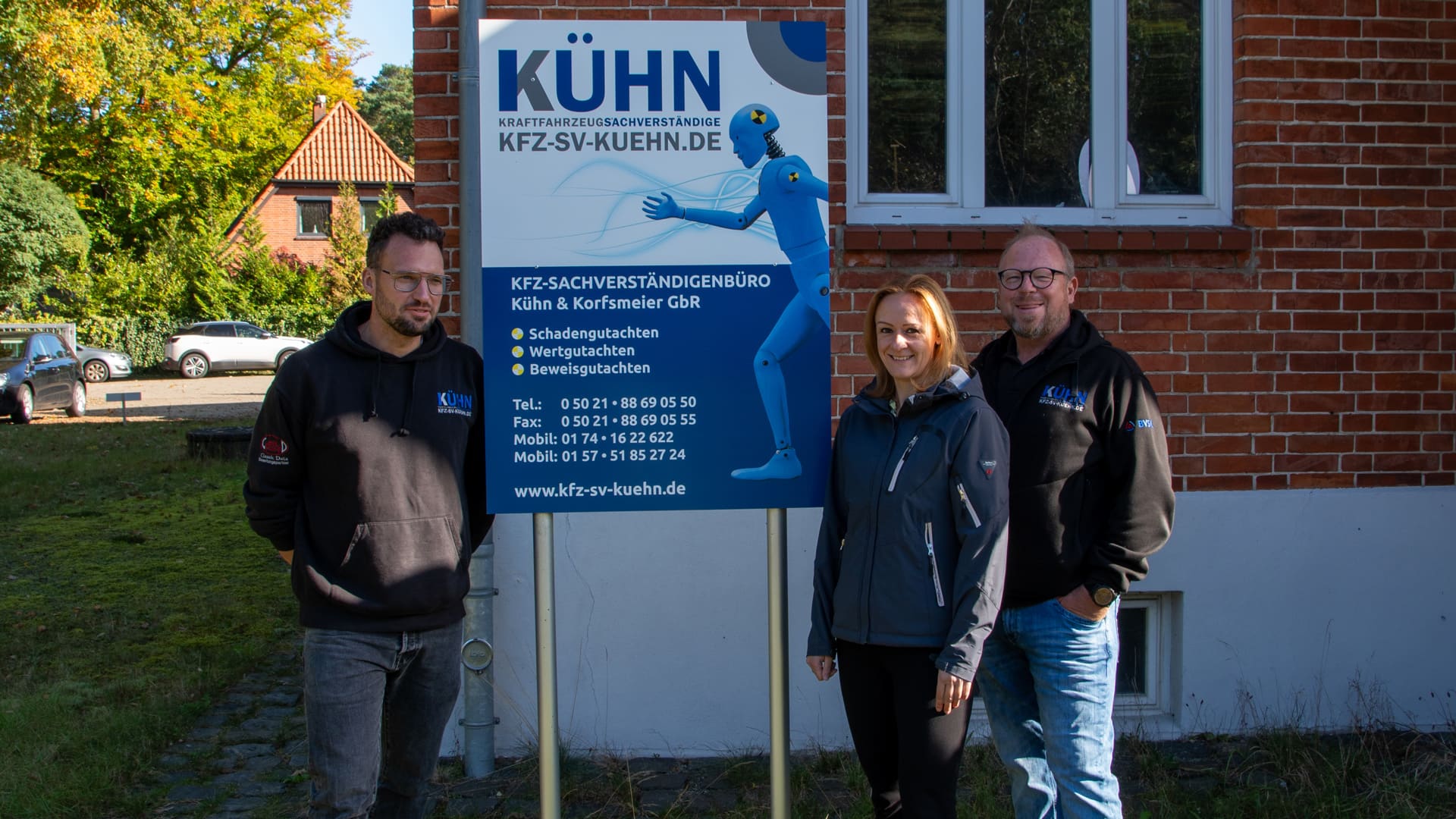 Das Team des Sachverständigenbüros vor dem Firmenschild am Standort Nienburg
