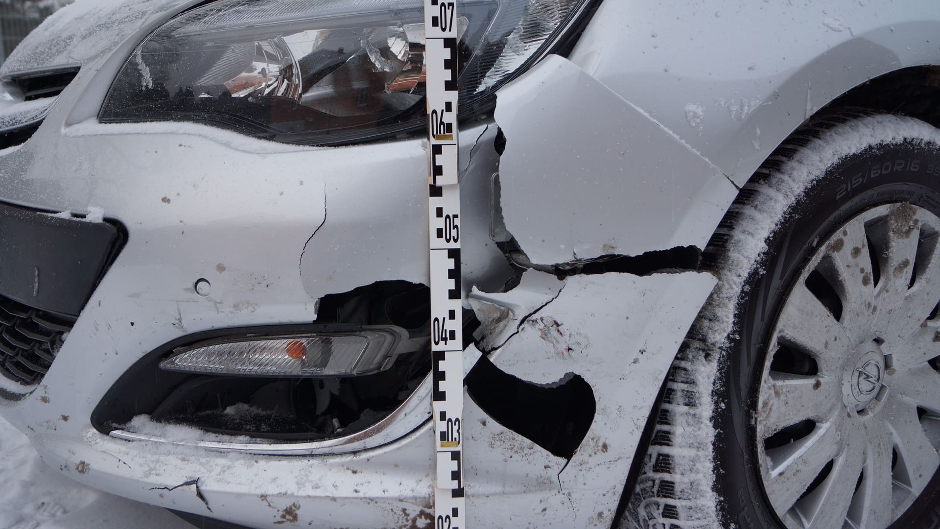 Frontschaden an einem Unfallfahrzeug, dokumentiert mit einer Messlatte